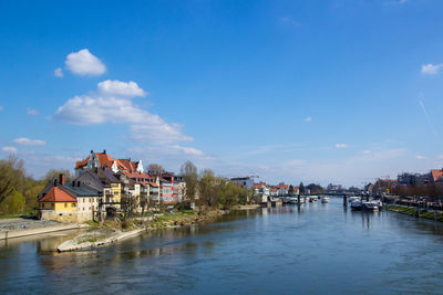 Buildings by river against sky