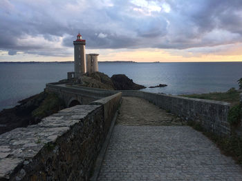 Lighthouse by calm sea against sky