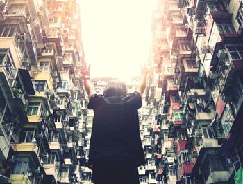 Rear view of man standing by stack of people in city