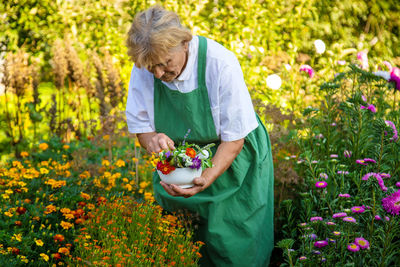 Female farmer holding flower plants on field