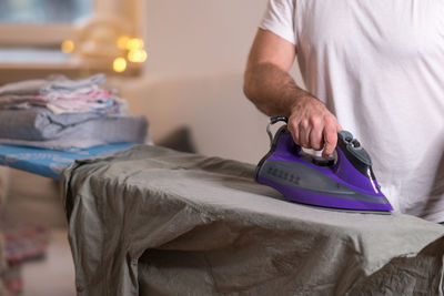 Midsection of man ironing shirt on board