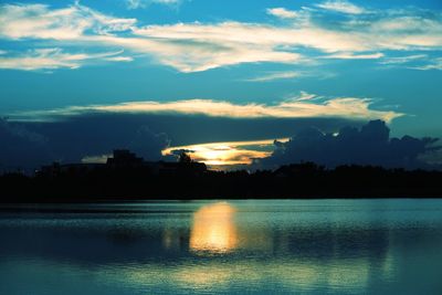 Silhouette trees by lake against sky during sunset