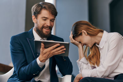 Young couple looking away while sitting on smart phone