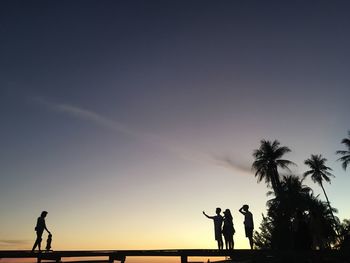 Silhouette people playing soccer against sky during sunset