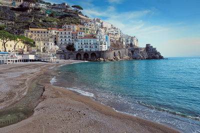 Buildings by sea against sky in city