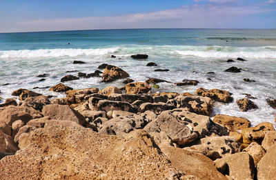 Scenic view of rocks on beach against sky