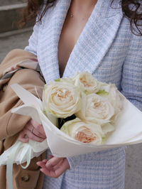 Midsection of woman holding bouquet of white roses