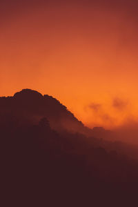 Scenic view of silhouette mountains against orange sky