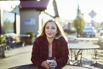 Young woman sitting at sidewalk cafe