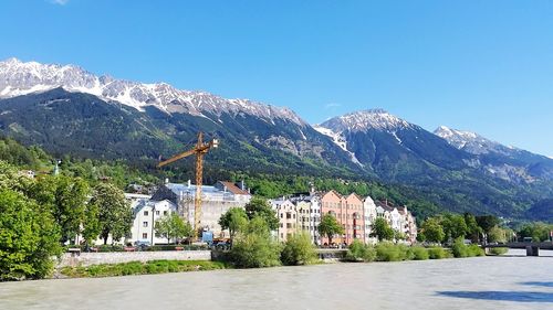 Scenic view of buildings and mountains against clear blue sky