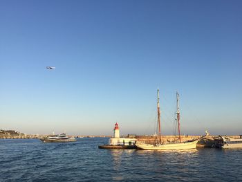 Sailboats in sea against clear blue sky