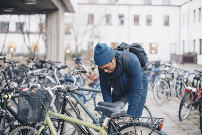 Young male university student unlocking bicycle in campus