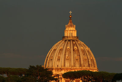 Dome of bernini's basilica of san pietro illuminated by the reddish light of the sunset.