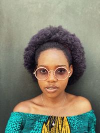 Portrait of woman wearing eyeglasses standing by wall