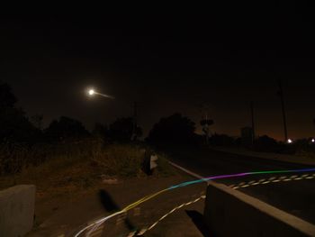 View of empty road along trees at night
