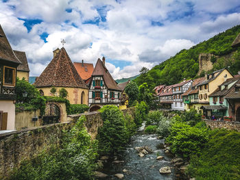 Houses by trees and buildings against sky