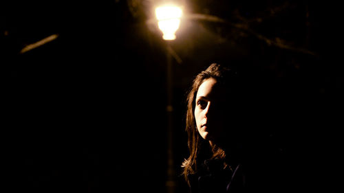 Close-up of woman by street light at night
