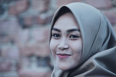 Close-up of woman wearing hijab against brick wall