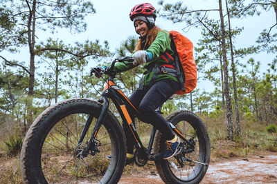 Full length of woman riding bicycle in forest