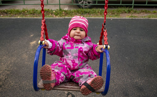 Full length of cute girl sitting on swing at playground