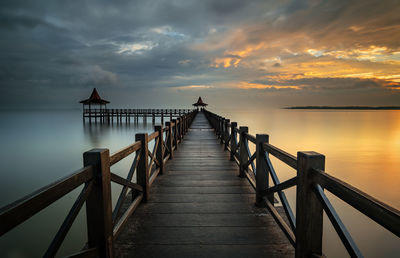 Pier over lake against sky during sunset