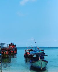 Fishing boats moored in sea against clear sky