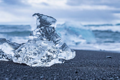 Close-up of beautiful iceberg chunk on shore of black sand at diamond beach