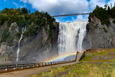 Scenic view of waterfall against cloudy sky