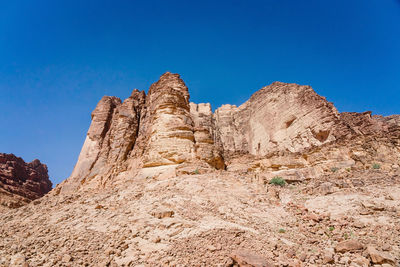 Low angle view of rock formations against clear blue sky