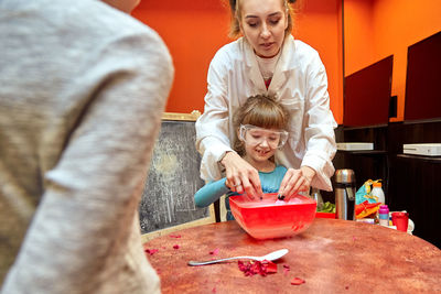 High angle view of mother and daughter sitting on table