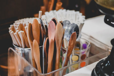 Close-up of spoons and straws in container on table