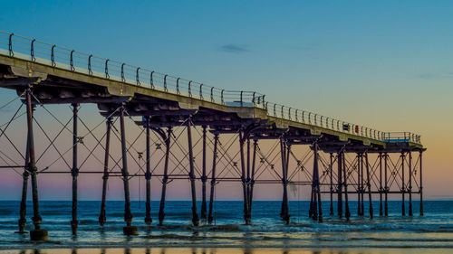 Bridge over calm blue sea against sky