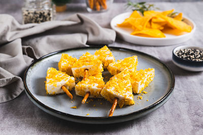 Fake christmas trees made from triangle cheese in nacho crumbles on a plate on a table