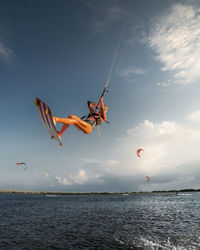 Professional athlete kitesurfer young caucasian woman doing a trick in the air against the backdrop 