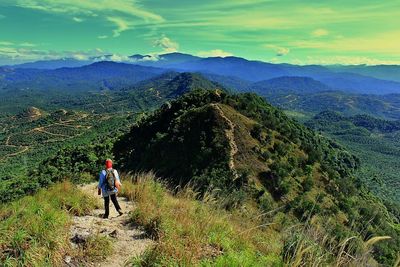 Rear view of man looking at mountains against sky