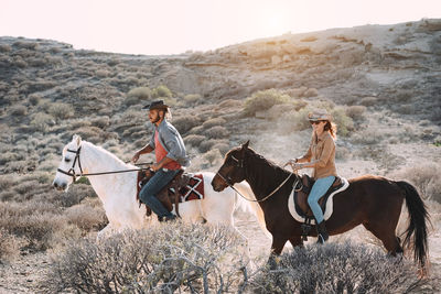 Young people riding horses doing excursion at sunset 
