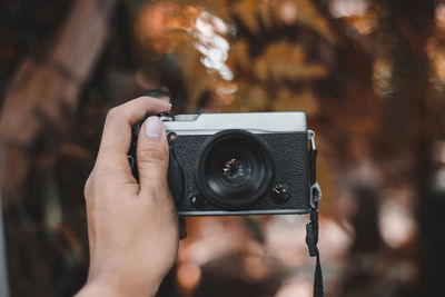 Cropped hand of woman photographing with camera outdoors