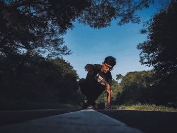 Man on road by trees against sky