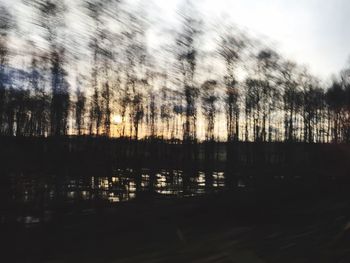 Silhouette trees by lake against sky during sunset