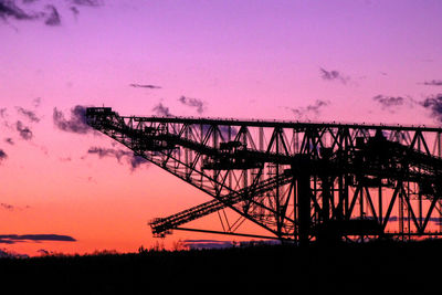 Silhouette cranes against sky during sunset