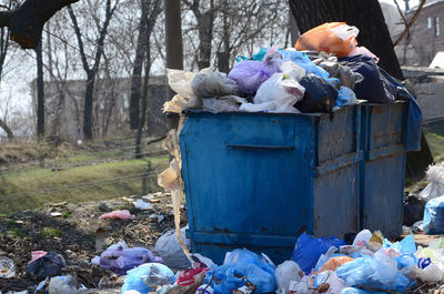Garbage bin on field against trees