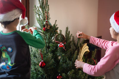 Two sisters decorating christmas tree in their home