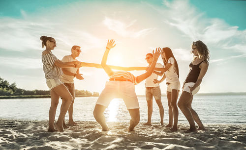 Happiness friends fun on beach under sunset sunlight in summer sunny day. funny group games.