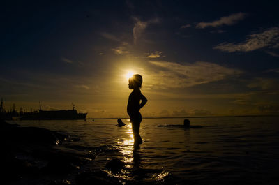 Silhouette woman on beach against sky during sunset