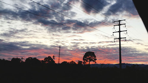 Low angle view of silhouette electricity pylon against sky during sunset