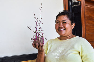 Portrait of young woman holding plant