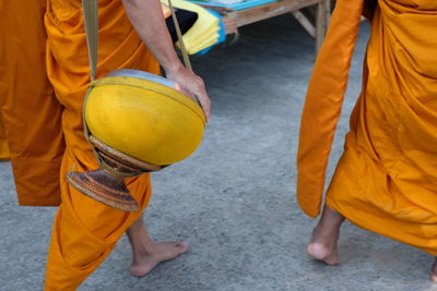 Low section of monk with bag walking on street