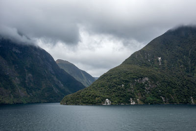 Scenic view of mountains and sea against cloudy sky