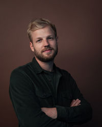 Portrait of young man standing against gray background