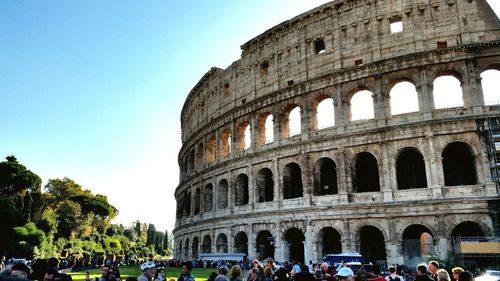 Tourists visiting colosseum against clear sky